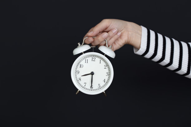 工作时间。重返工作岗位。手里拿着钟的女人。孤立的背景。图片下载