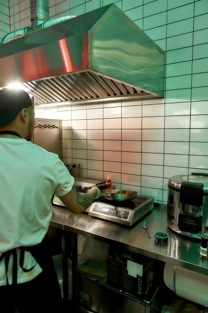 男厨师在商业厨房工作，用平底锅和火烹饪猪肉或牛肉图片下载