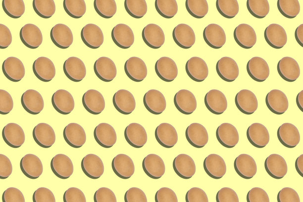 许多鸡蛋排成一行排列在黄色的背景上，生食配料的背景，艺术的背景，复活节彩蛋，图案和纹理的背景图片下载