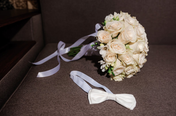 白色蝴蝶结和一束白色玫瑰在一个棕色的背景图片下载