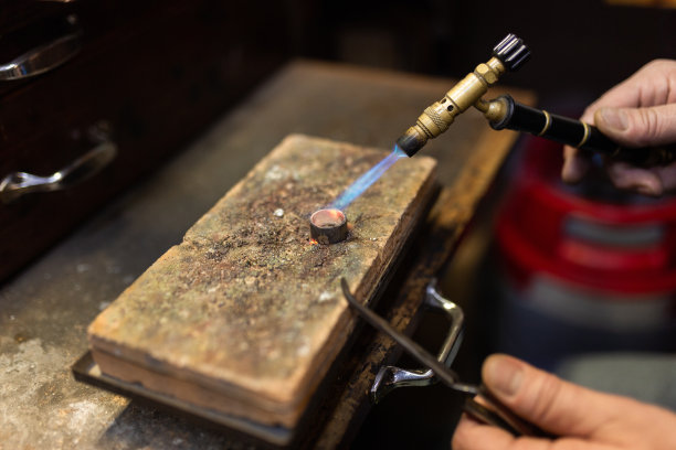 金匠珠宝商在工作台上焊接一个银戒指。图片下载