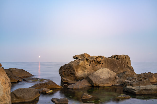 暮色笼罩着荒凉的岩石海滩、海岸线和大海。大海和岩石在夜间的广角视野。图片下载