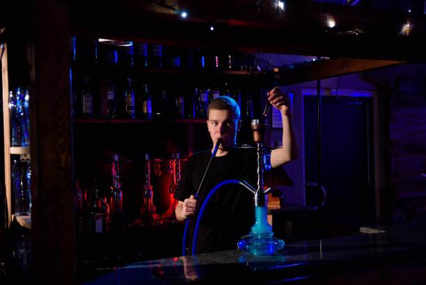 男子抽传统的水烟管，在水烟咖啡馆吐出烟雾。图片下载
