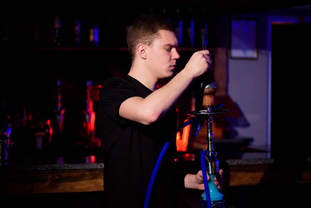 男人使水烟。现代水烟与椰子木炭放松和水烟。图片下载