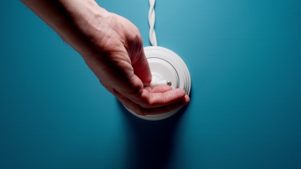 在蓝色墙壁上的一个拨动开关上的男性手开关图片下载