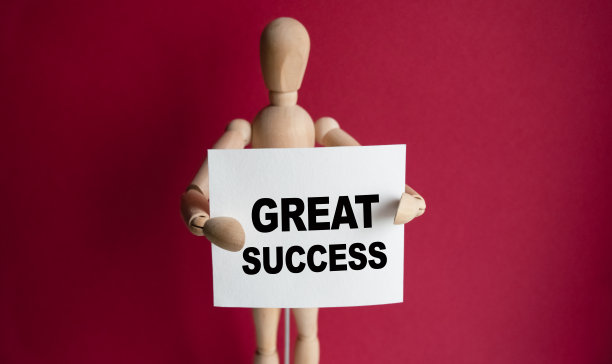 木制的男人手里拿着一个白色的牌子，上面写着“伟大的成功”。文字的内容对企业的经营理念和市场营销都有一定的影响。图片下载