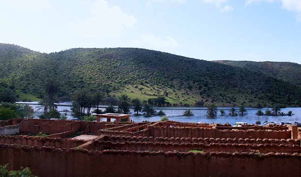 一座古老的泥建筑，靠近山坡上的一个湖。图片下载
