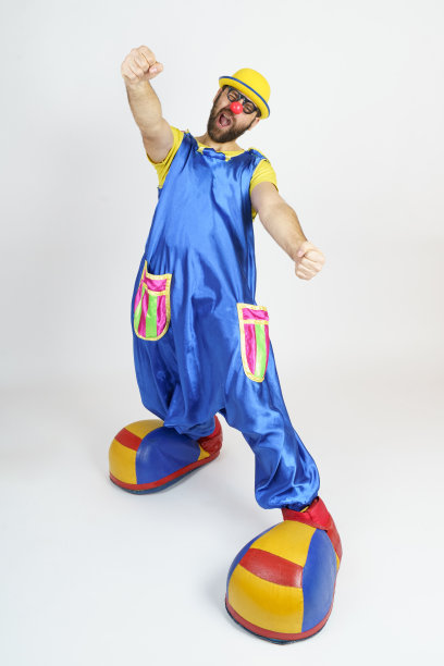 一个穿着亮蓝色和黄色套装的小丑在驾驶一辆汽车图片下载