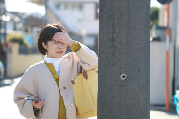 一个女人踩着智能手机走路，头撞到了电线杆上图片下载