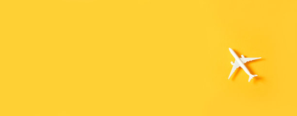 黄色背景上的微型玩具飞机。乘飞机旅行。水平的旗帜。图片下载