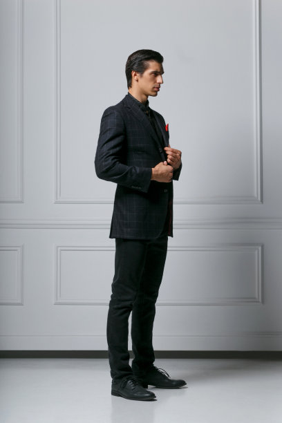 一个时尚自信的年轻人穿黑色西装的全长照片在侧面，在白色的背景。图片下载