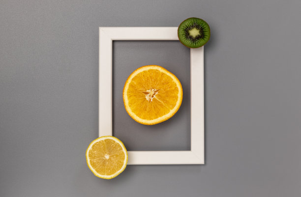 灰色背景上的白色矩形，半块橙子，柠檬和猕猴桃。图片下载