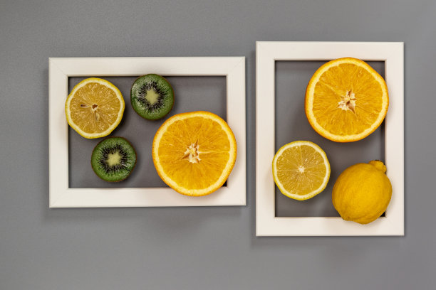 两张白色相框里装着一半的柑橘和猕猴桃。图片下载