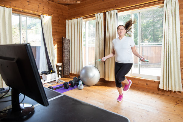 一个女人在家里的电脑屏幕前无绳跳绳图片下载