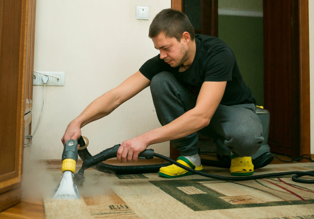 用蒸汽真空吸尘器清洗地毯的过程。清洁公司的一名员工用蒸汽清洗地毯。图片下载