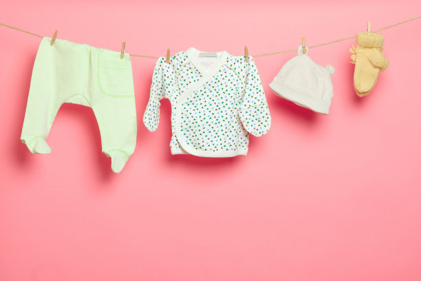 粉红色背景上晾衣绳上的婴儿衣服-图片图片下载