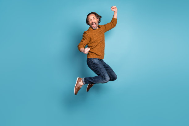 成熟英俊的全尺寸照片兴奋疯狂微笑的男人在成功中跳跃胜利孤立在蓝色背景图片下载