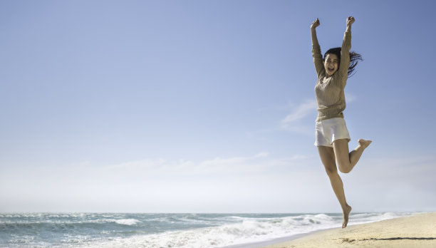 夏日休闲度假概念与复制空间，快乐悠闲的亚洲女性微笑跳上海滩图片下载