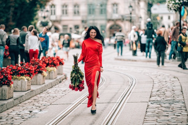 迷人的年轻女子在红色性感连衣裙摆姿势与一束红玫瑰。有轨电车轨道上一个性感的黑发女人的照片。有选择性的重点,filmgrain图片下载