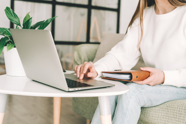 女人用笔记本电脑在笔记本上写字图片下载