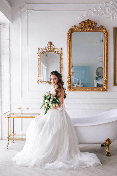 美丽的黑发新娘摆姿势在工作室白色礼服与婚礼花束图片下载