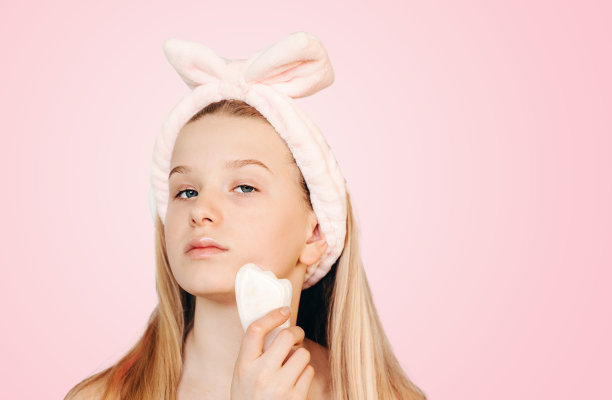 年轻女孩做中国传统刮沙面部按摩，家庭护肤常规，SPA放松，面部和皮肤护理背景图片下载