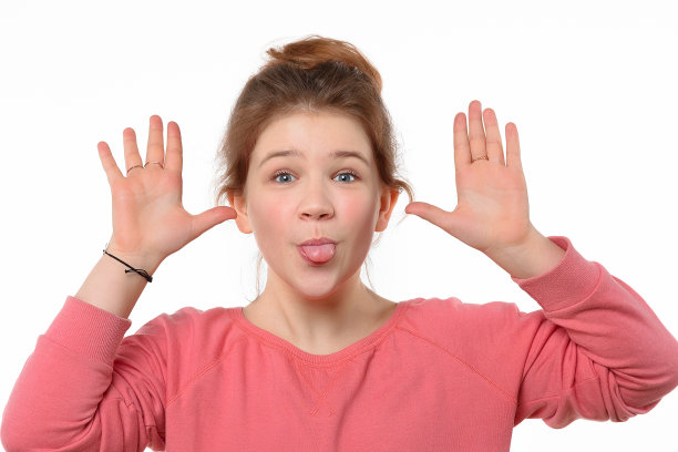 快乐的年轻女孩做鬼脸和展示她的舌头的特写肖像。白色背景图片下载