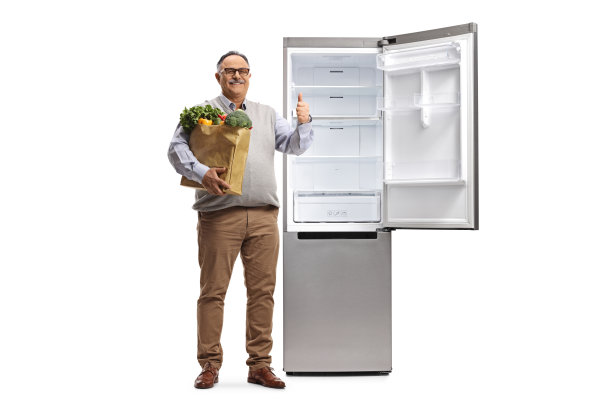 一位老人拿着一个购物袋站在一个空冰箱旁边，竖着大拇指的全身像图片下载