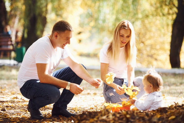 一个快乐的年轻的家庭一起在秋天的公园里休息图片下载