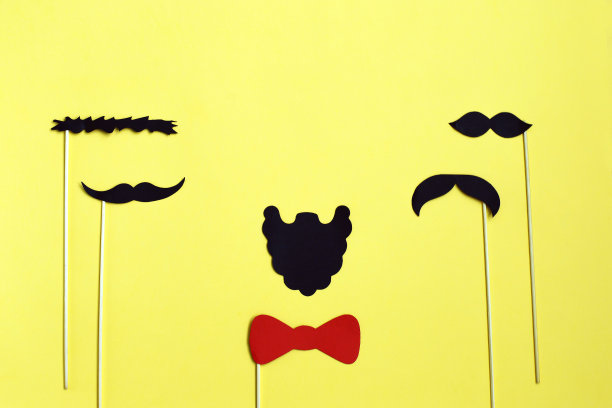 许多黑色的纸胡子在黄色的背景。俯视图，平放。文本的拷贝空间。图片下载