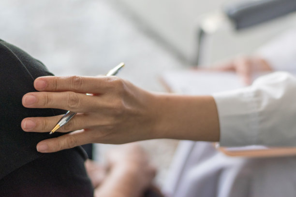 身穿白色制服大褂的专业医生面谈辅导女病人:医生在会诊时在病人表上写下:医院/诊所的医疗保健专业理念图片下载