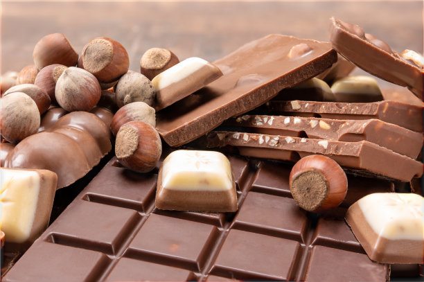 带坚果的巧克力棒。侧面的美食巧克力片与榛子在模糊的背景。各种巧克力的背景。牛奶黑可可棒图片下载