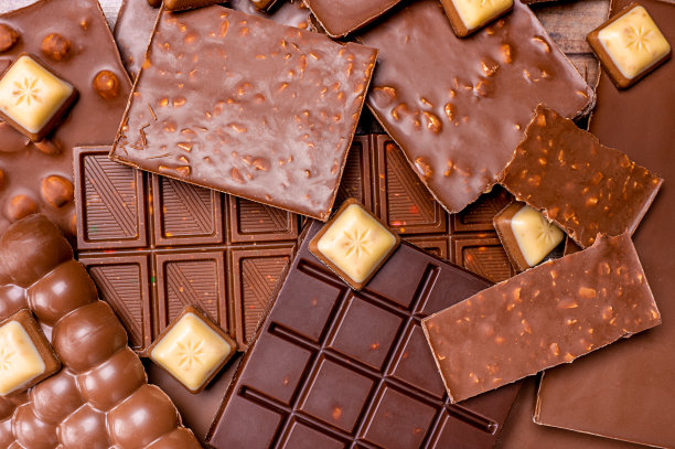 榛仁、杏仁、牛奶和黑巧克力。俯视图的巧克力条与巧克力片的背景。图片下载