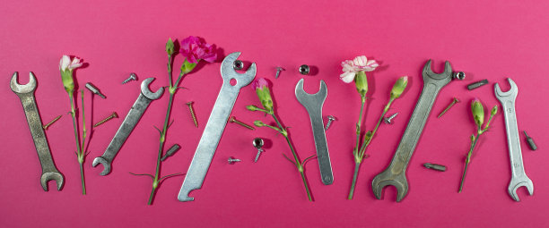 劳动节背景概念、5月1日概念。扳手和丁香粉红色康乃馨花在粉红色的背景。图片下载