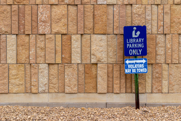图书馆的停车标志前面的现代石灰石墙与粗糙的天然石材砖图片下载