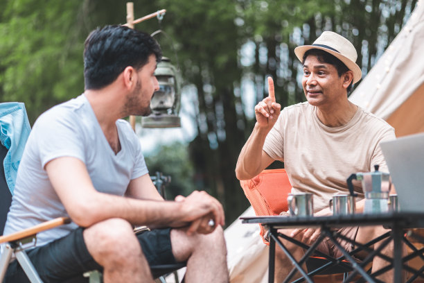 夏季露营在山上，以云杉林为背景。后景一群游客围坐在篝火旁休息，享受帐篷附近的新鲜空气。全家欢度假期，一起玩。图片下载