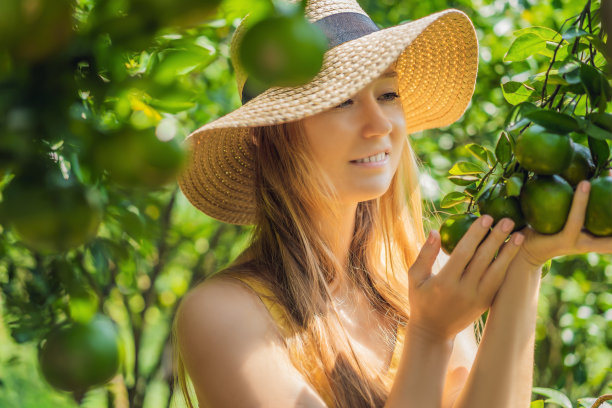 美丽的农妇在有机农场收获橙子，快乐的女孩在花园里收获橙子，农业和种植概念图片下载