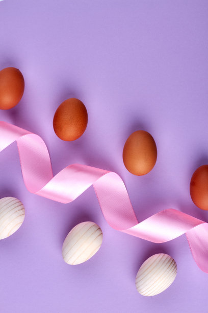 俯视图漩涡丝绸磁带和鸡蛋在紫色的背景。图片下载