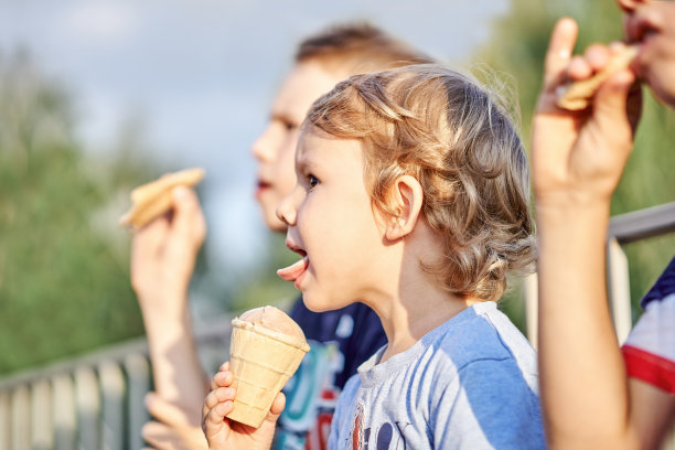 小男孩和哥哥们坐在公园里吃冰淇淋图片下载