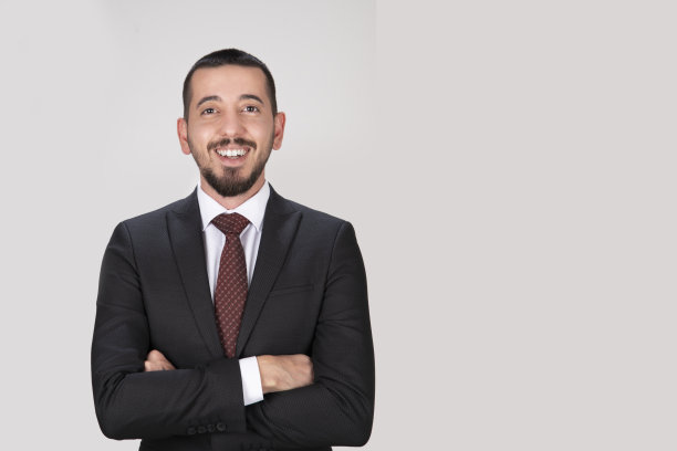 这是一个年轻成功的股票经纪人的特写，他穿着西装，打着领带，面带微笑，用手指指着一张股票照片图片下载