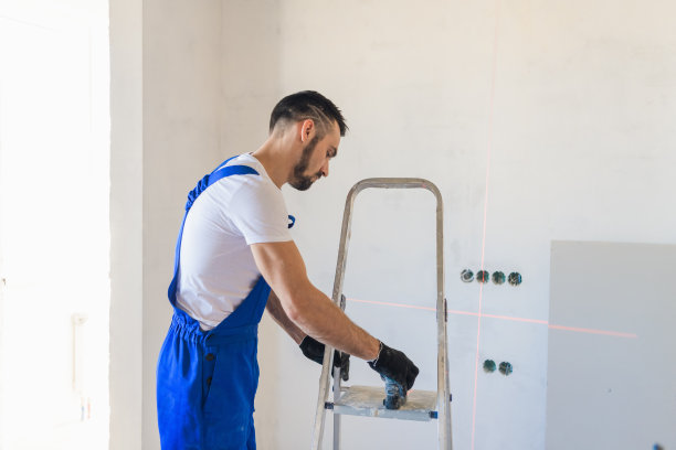 工人使用一个活梯和一个激光水平仪图片下载