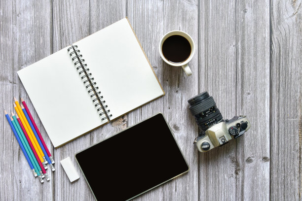 静物，商务或旅行者备忘录概念，顶部视图图像打开笔记本与复古相机咖啡彩色铅笔和平板与空白页上的老棕色木制背景，添加文本图片下载