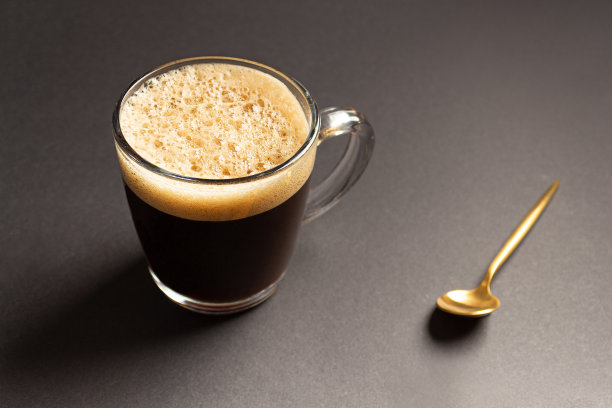 早晨的浓缩咖啡，在黑色的背景上，用蒸汽的玻璃杯盛着图片下载