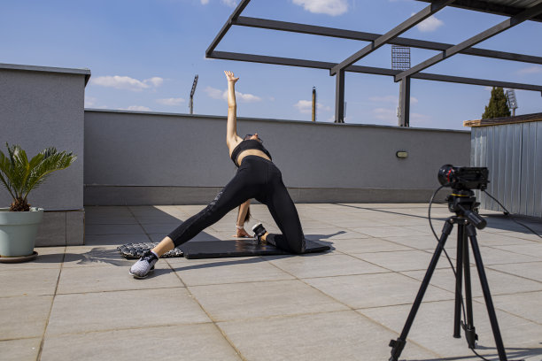 穿着运动服的漂亮年轻女子在阳台上制作社交媒体视频图片下载