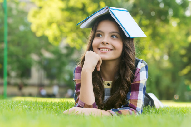 这是我的阅览室。快乐的孩子捧着书躺在绿色的草地上。图书馆借阅。阅读和素养教育。学校图书馆。藏书。信息和知识。9月1日图片下载
