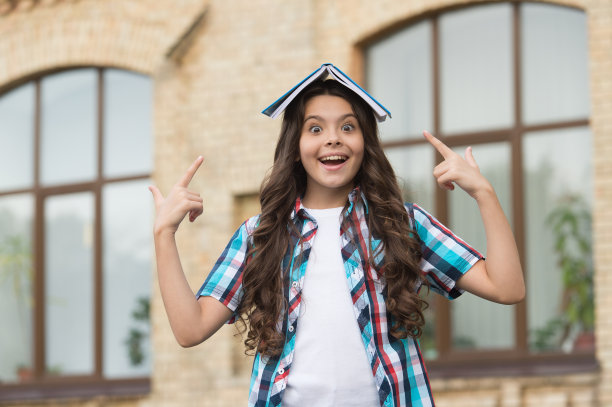 快乐的小朋友在户外用手指指着课本、知识图片下载