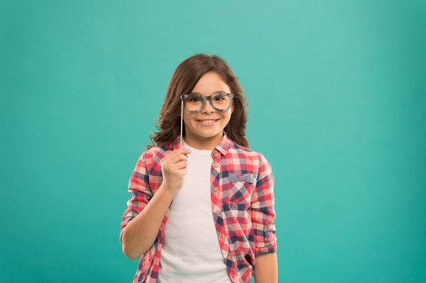 可爱的书呆子。聪明的宝宝。小孩抱可爱的眼镜照相亭道具派对配件。孩子迷人的绿松石背景。女孩拿着眼镜参加派对。儿童用眼镜复制空间。派对图片下载