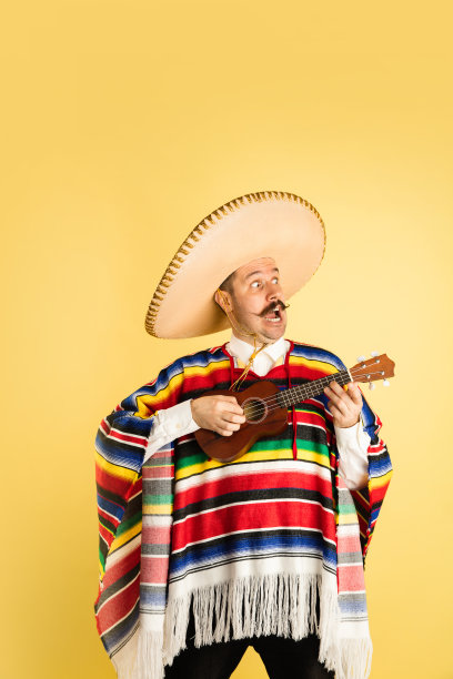 年轻男子的肖像在明亮的衣服，雨披孤立在黄色的背景图片下载