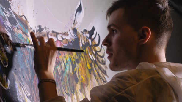 艺术家设计师在墙上画了一只鹰。工匠装饰用丙烯酸油彩作画。穿着油漆外套的画家。室内。图片下载