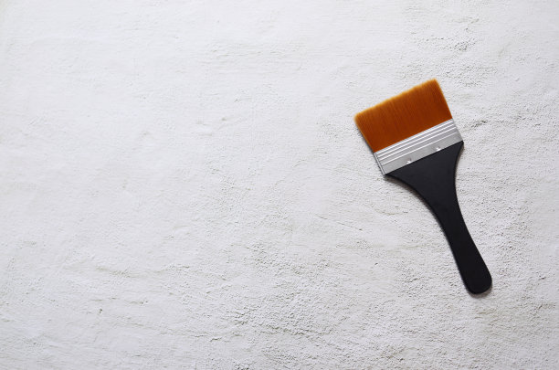 白色混凝土地板上的丝刷，橙色刷毛和黑色把手图片下载